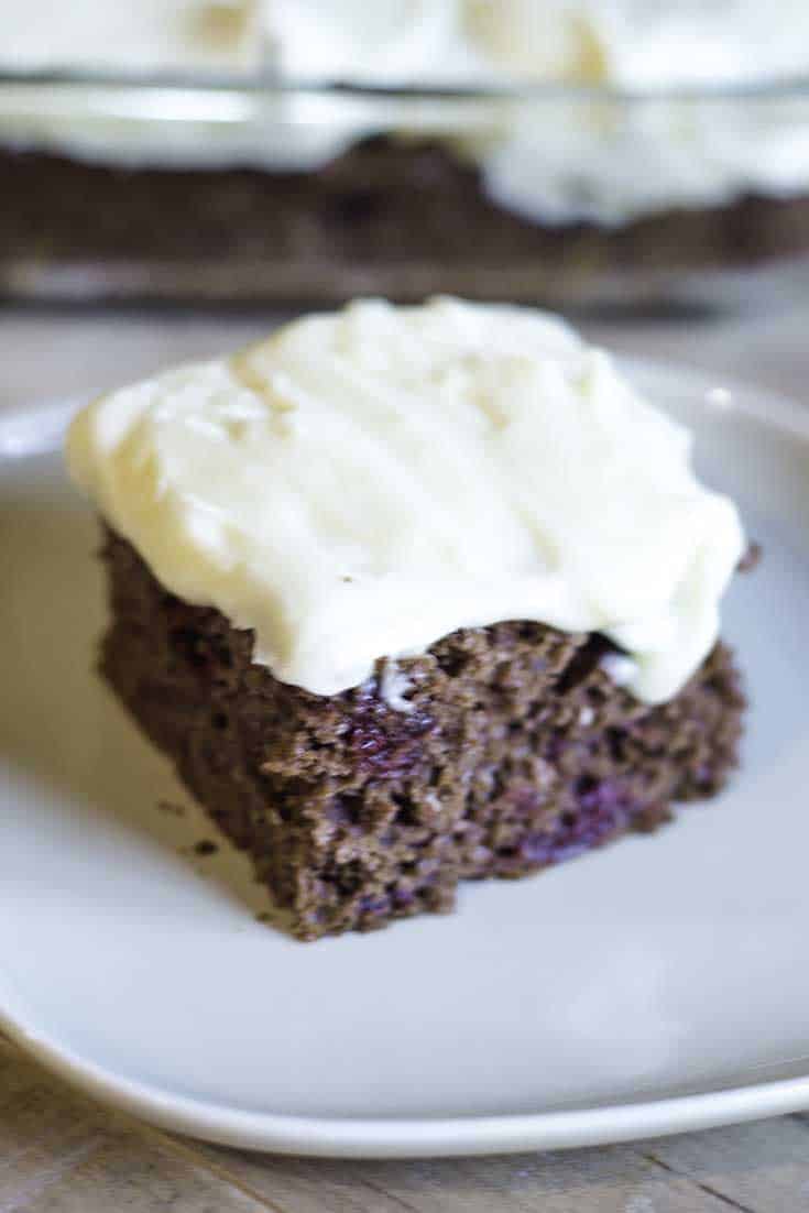 A slice of cherry devil's food cake topped with cream cheese frosting