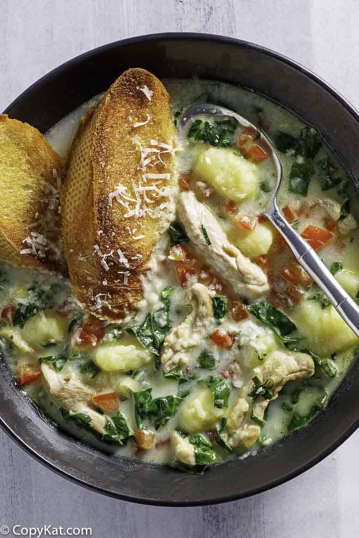a bowl of homemade Macaroni Grill chicken Toscana soup and 2 pieces of toasted bread in it.