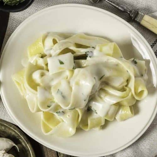 Alfredo sauce over pasta on a plate.