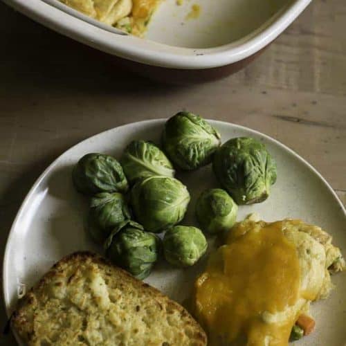 tuna stuffed crescent roll casserole on a plate with bread and Brussels sprouts