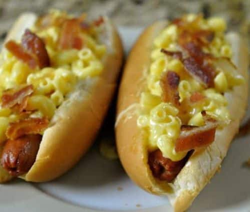 two hot dogs topped with truffle macaroni and cheese and bacon