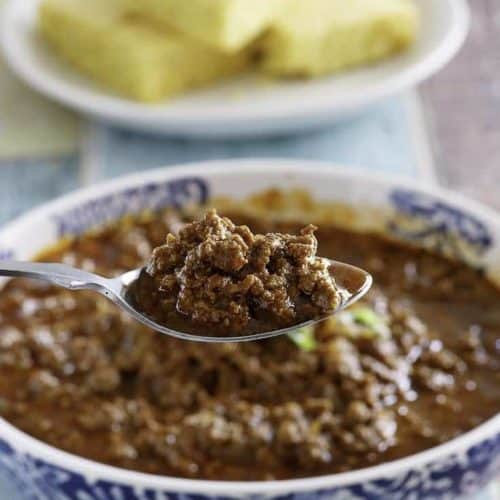 A spoon of copycat Chilis Original style chili over a bowl of it.