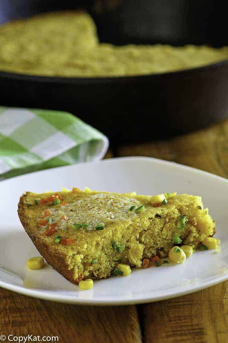a plate with a slice of jalapeno cornbread with melted butter on top.