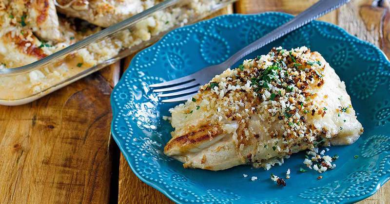 A serving of Longhorn parmesan crusted chicken on a decorative blue plate. The focus is on the golden-brown, crispy panko and herb crust covering the tender chicken breast.