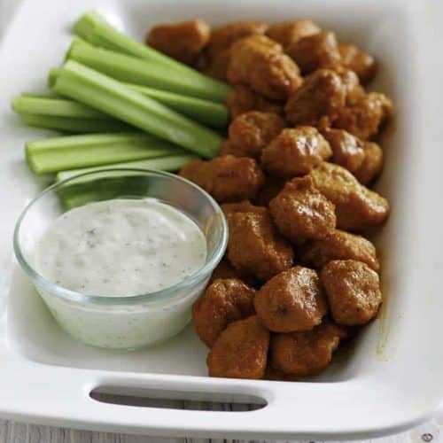 Boneless Buffalo Chicken Bites on a platter with blue cheese dressing and celery sticks