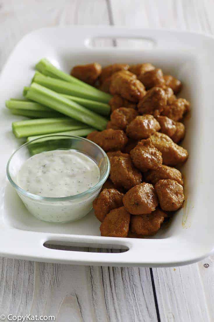 Boneless Buffalo Chicken Bites, blue cheese dressing, and celery sticks on a platter
