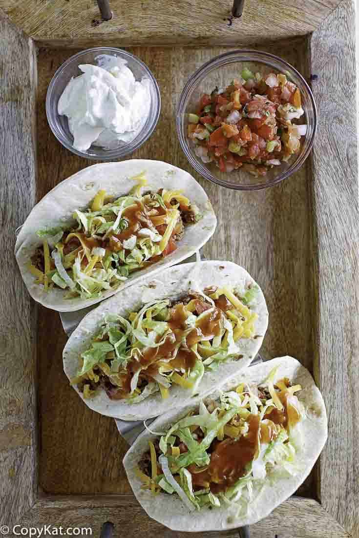 3 tacos with homemade Taco Bell taco sauce drizzled on top.