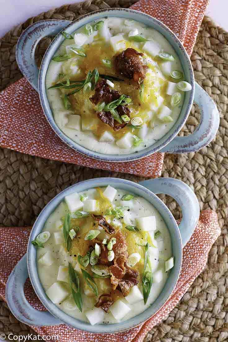 two bowls of baked potato soup with toppings of cheese and bacon