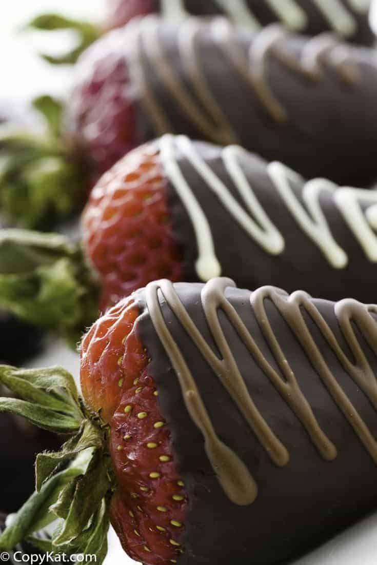 Three chocolate covered strawberries on a plate.