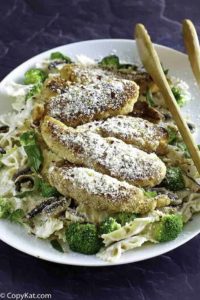 Parmesan crusted chicken tenders and pasta on a plate.