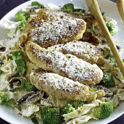 Parmesan crusted chicken tenders and pasta on a plate.