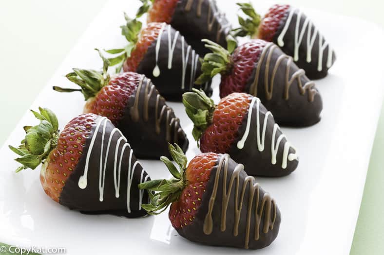 Chocolate covered strawberries on a plate, with chocolate drizzle on them