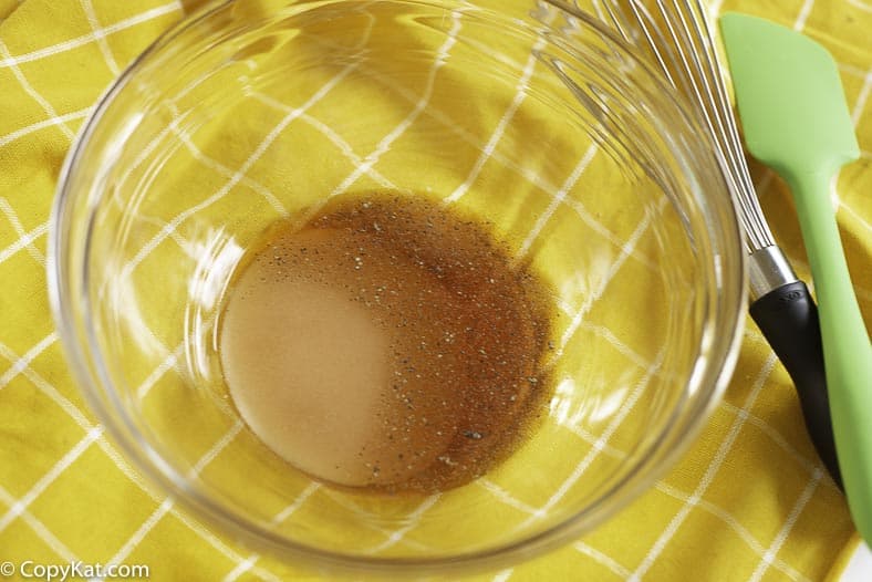 A bowl of red wine vinegar, salt, pepper, and sugar.