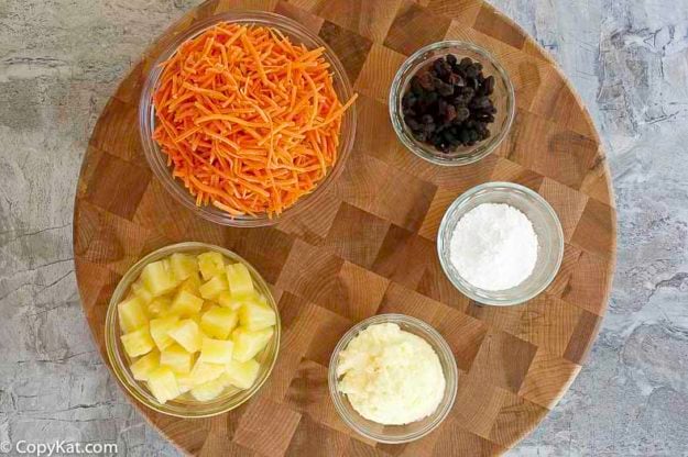 Ingredients to make carrot raisin salad. Shredded Carrots, pineapple, powdered sugar, mayonnaise, and raisins.