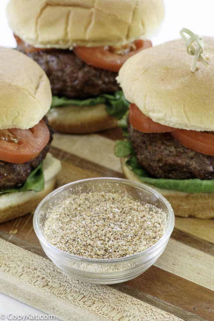 homemade burger seasoning and hamburgers on a wood cutting board.