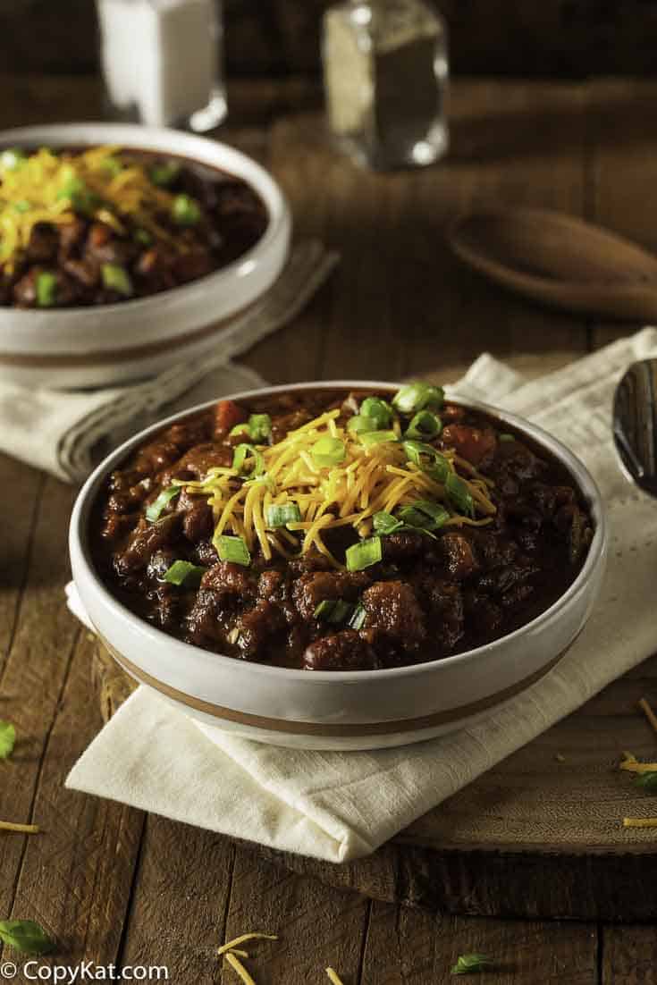 A bowl chili topped with cheese and green onions