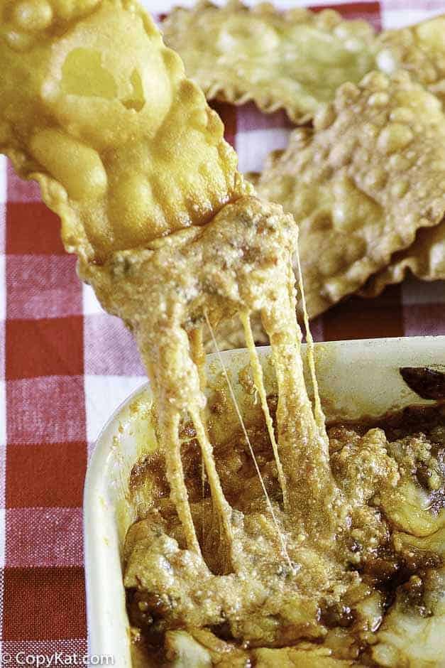 a pasta chip dipping into cheesy lasagna dip