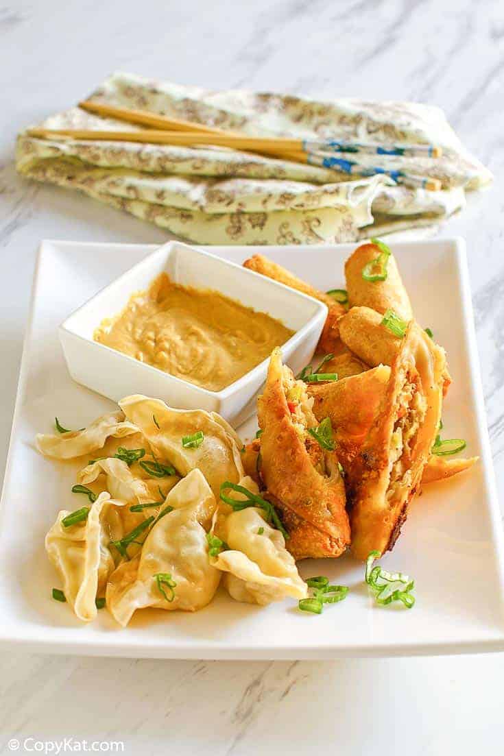 Chinese hot mustard, dumplings, and egg rolls on a platter