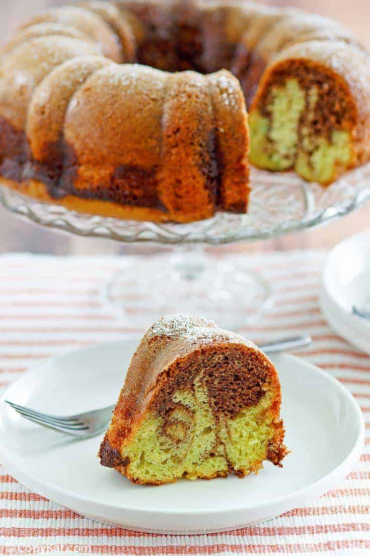 a slice of chocolate pistachio bundt cake in front of the cake on a stand