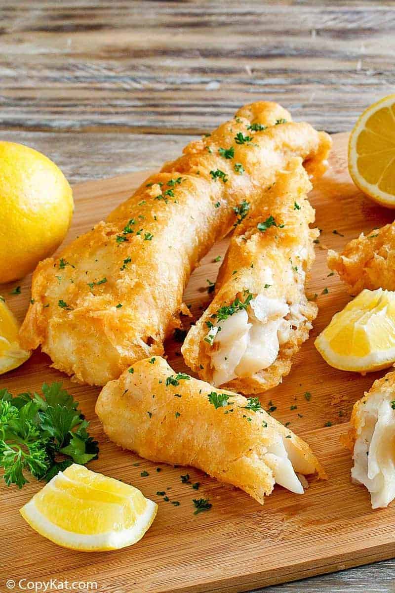 Homemade Captain D's batter dipped fish and lemons on a wood platter