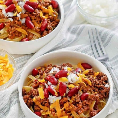 bowls of Cincinnati chili topped with cheese, onions, and kidney beans