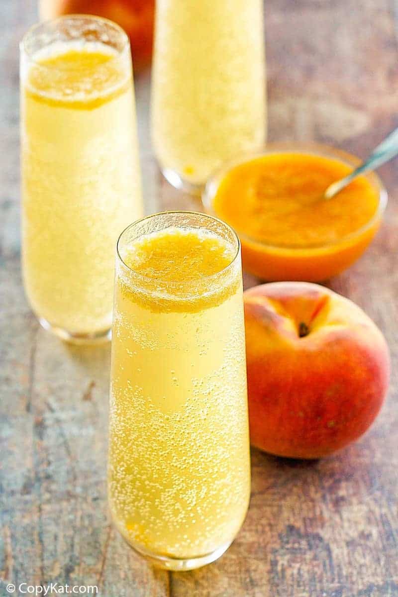 homemade Harry's Bar Bellini cocktails, a fresh peach, and peach puree