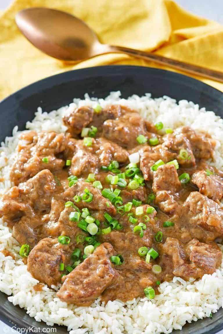 beef tips and gravy over rice on a black plate