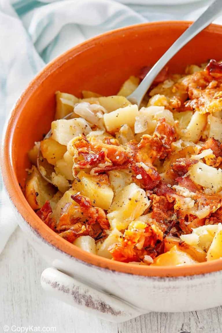 Crockpot cheesy potatoes with bacon and a spoon in a bowl