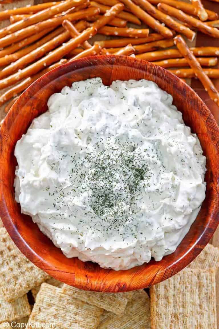 a bowl of dill pickle dip, pretzel sticks, and crackers