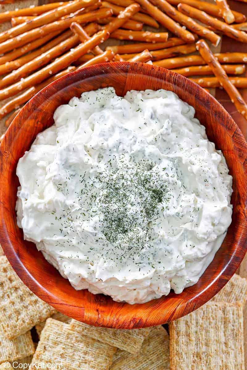 a bowl of dill pickle dip, pretzel sticks, and crackers