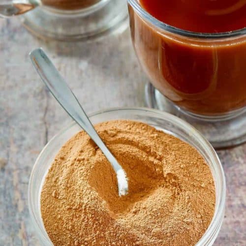homemade Swiss Miss hot cocoa mix in a bowl next to mugs of hot cocoa