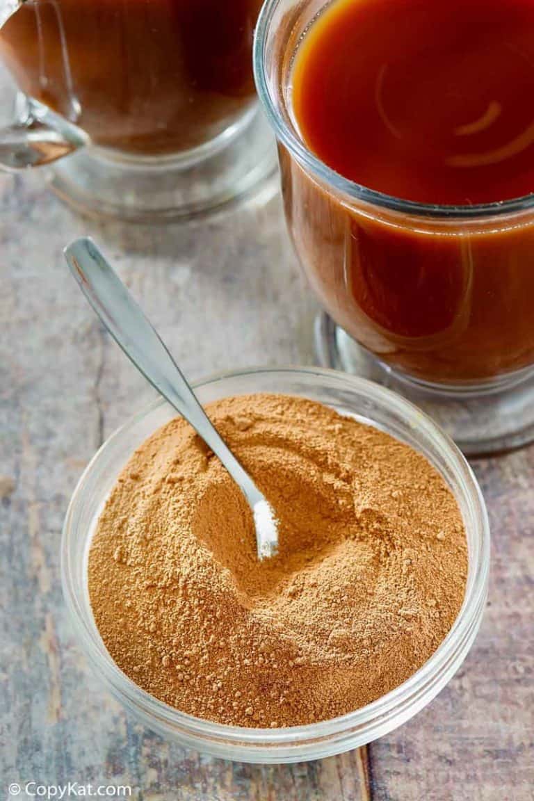 homemade Swiss Miss hot cocoa mix in a bowl next to mugs of hot cocoa