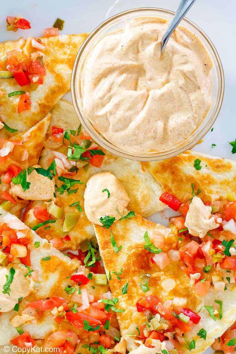 a bowl of homemade Taco Bell quesadilla sauce and quesadillas on a plate