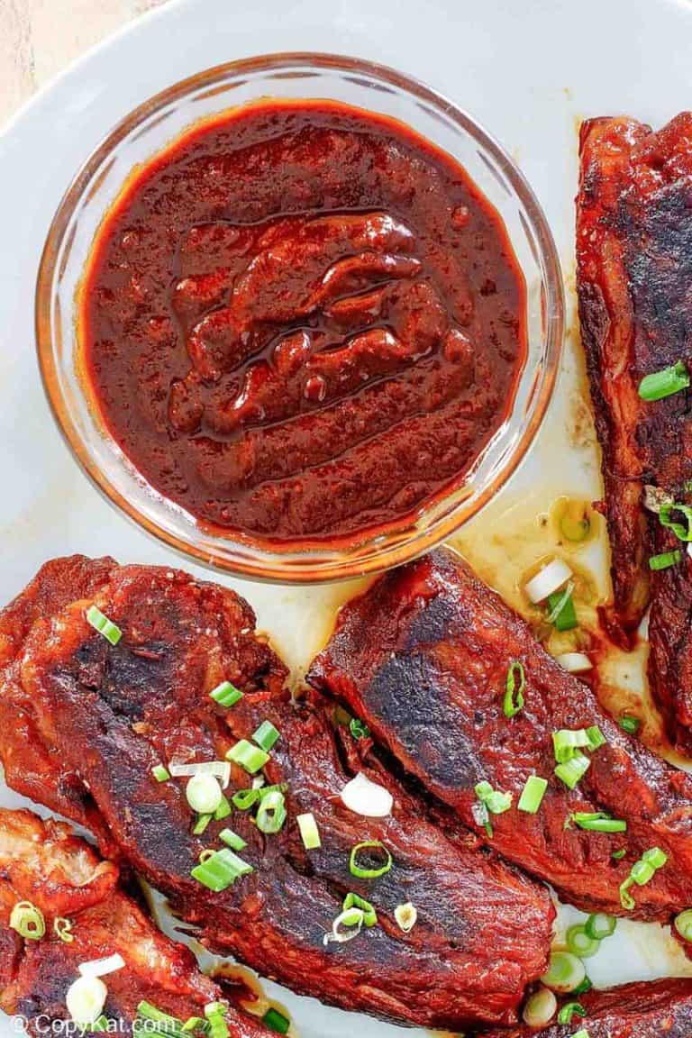 a bowl of homemade Sonny's BBQ sauce and ribs on a plate