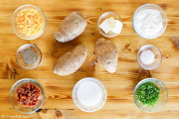 Ingredients for potato casserole including russet potatoes, cheese, bacon, sour cream, and butter.