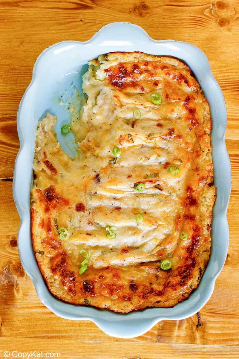 Overhead view of a baked potato casserole in a blue dish with a large scoop removed.