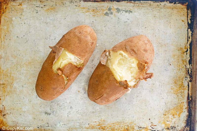 partially peeled boiled russet potatoes on a baking sheet