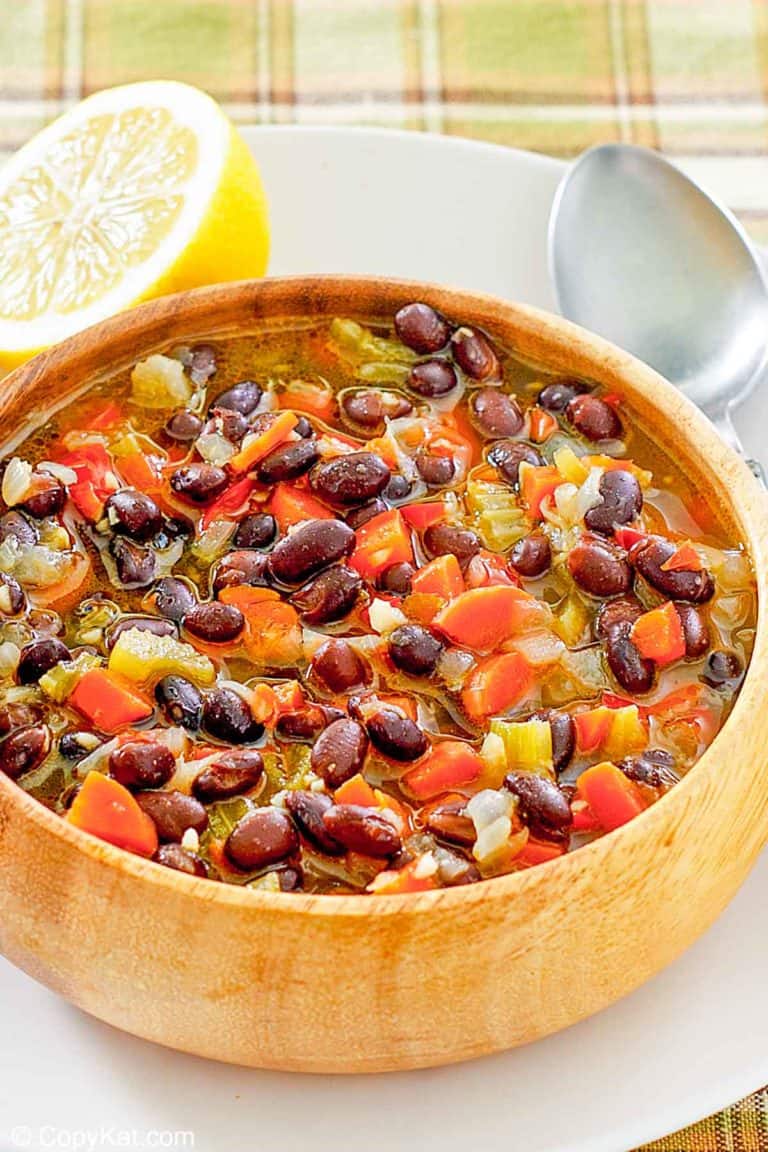 a bowl of homemade Panera black bean soup, a spoon, and half of a lemon