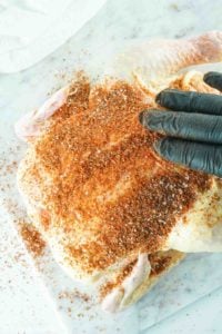 rubbing seasoning on a whole chicken