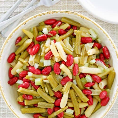 three bean salad, fork, plates, and wooden spoon
