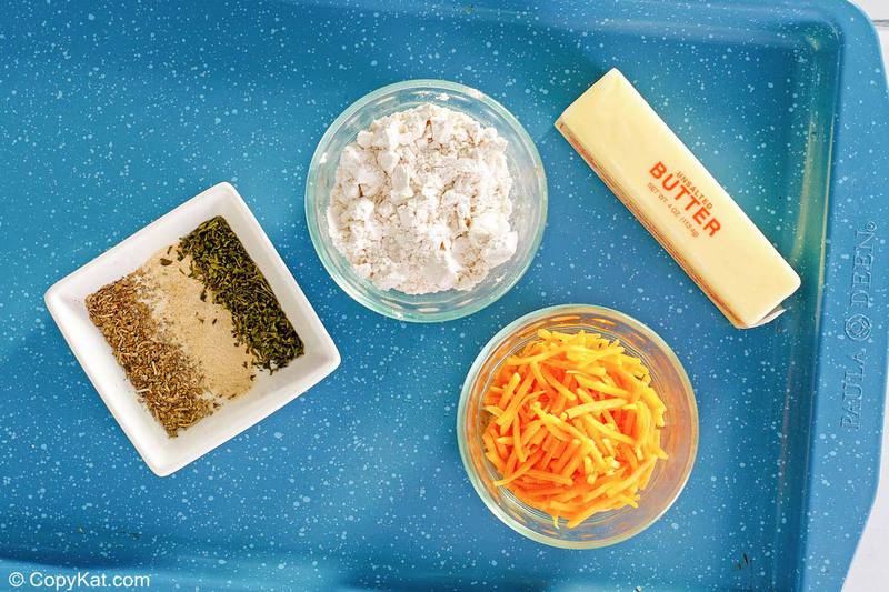Bisquick mix, butter, shredded cheddar cheese, and spices on a blue tray.