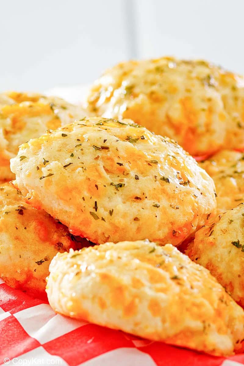 A basket lined with red and white paper filled with warm, garlic-buttered Red Lobster cheddar bay biscuits.