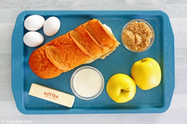 apple bread pudding with caramel sauce ingredients on a tray.