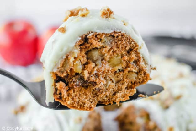 a slice of apple spice cake with cream cheese frosting on a cake server.