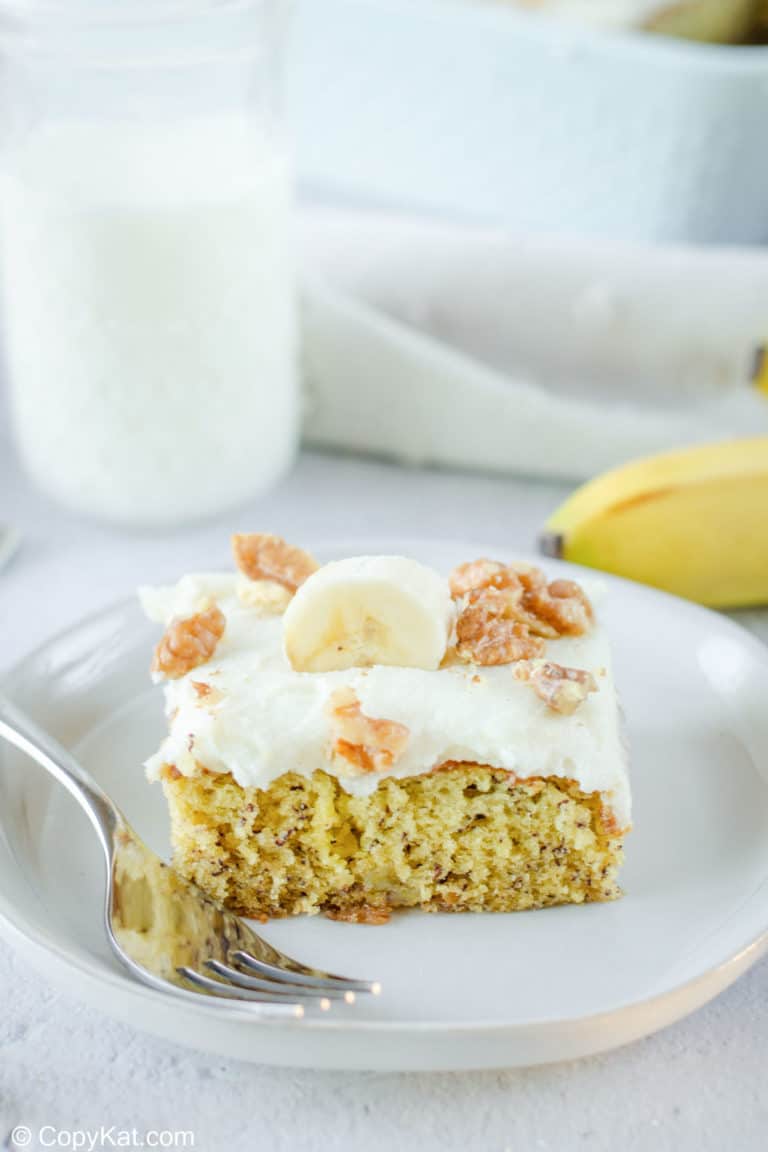banana cake slice and a fork on a plate and a glass of milk.