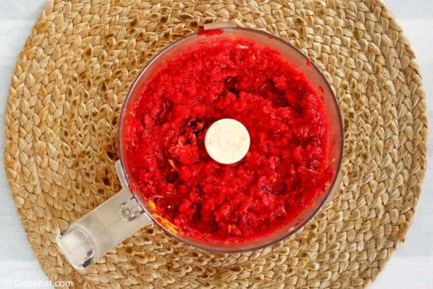 chopped fresh cranberries and an orange in a food processor bowl.