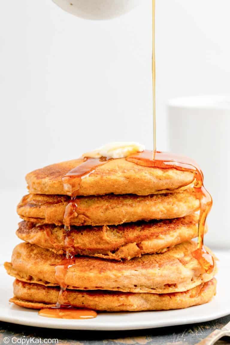 a stack of homemade IHOP pumpkin pancakes with syrup flowing over them.