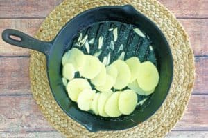 thinly sliced garlic and potatoes in a skillet.