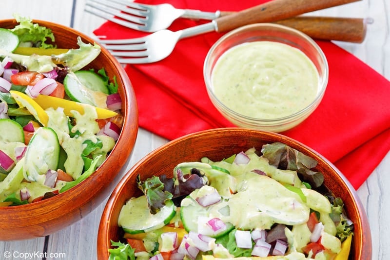 homemade Chick Fil A avocado lime ranch dressing in a bowl and on two salads.