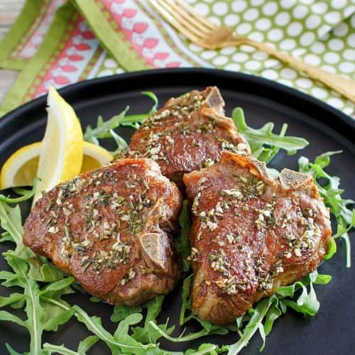three pan seared lamb chops on a plate.